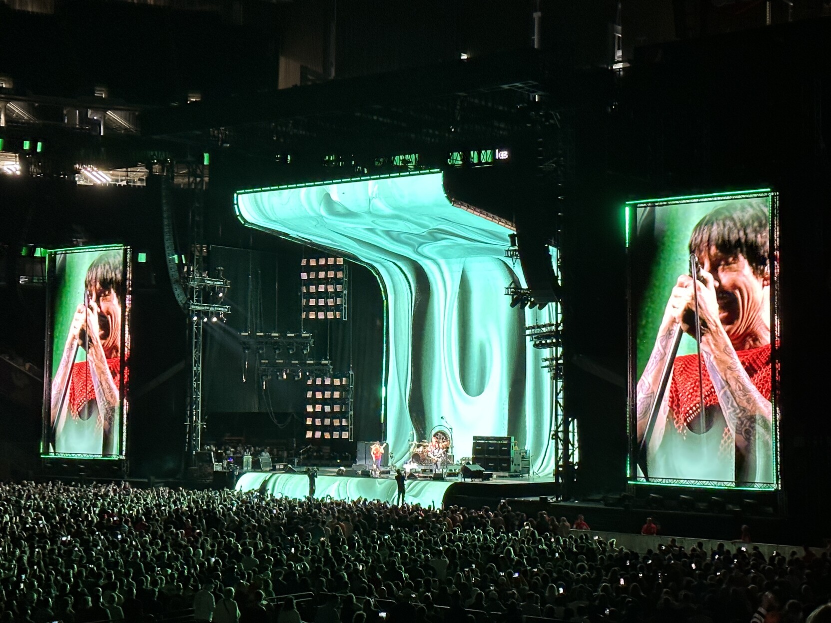 Crowd shot of the stage with two large video boards on each side that are displaying close-up video of the lead singer Anthony Kiedis
