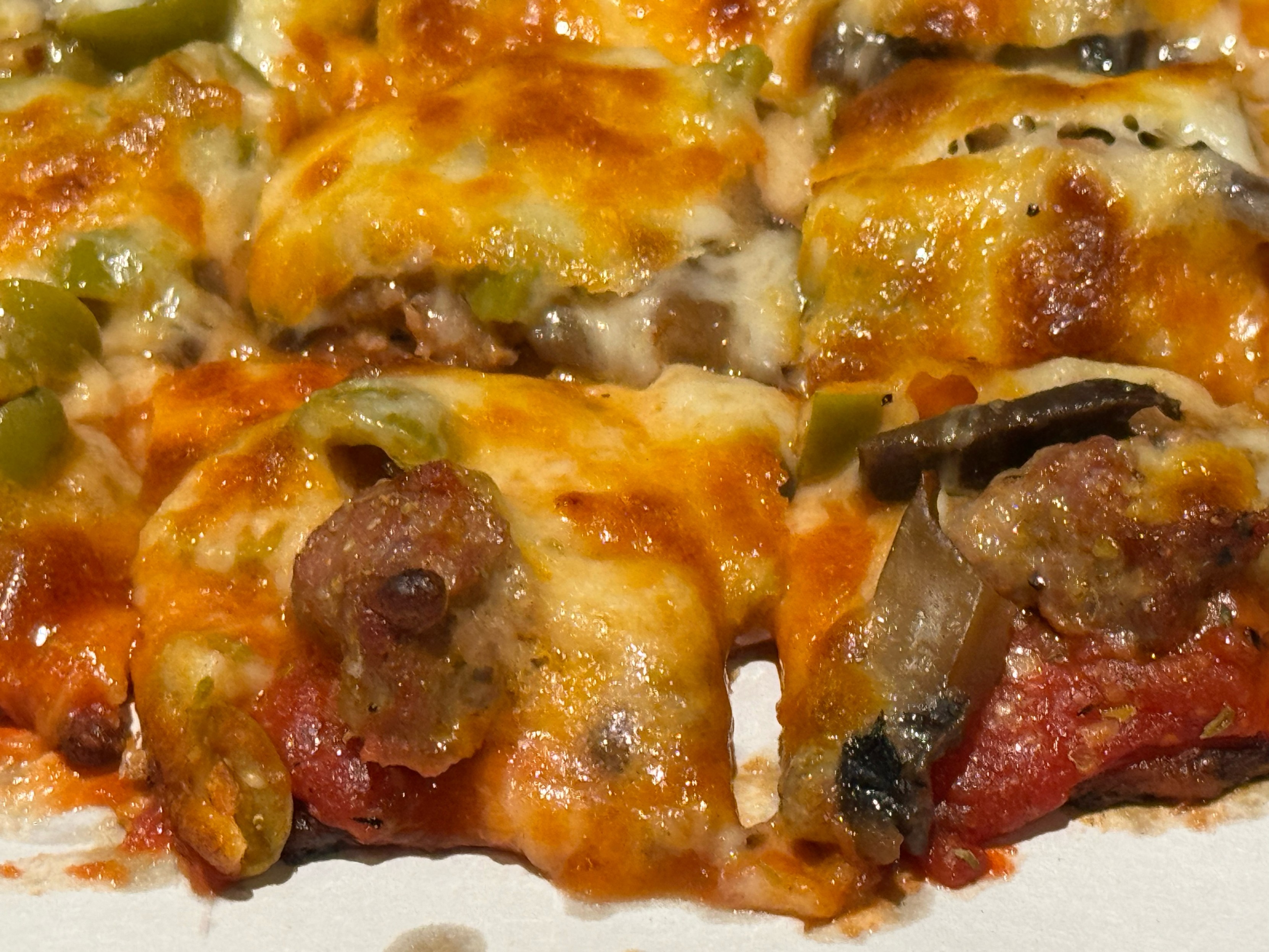 Close-up pic of a Carbone’s small 7-inch pizza with sausage, mushroom and green olive