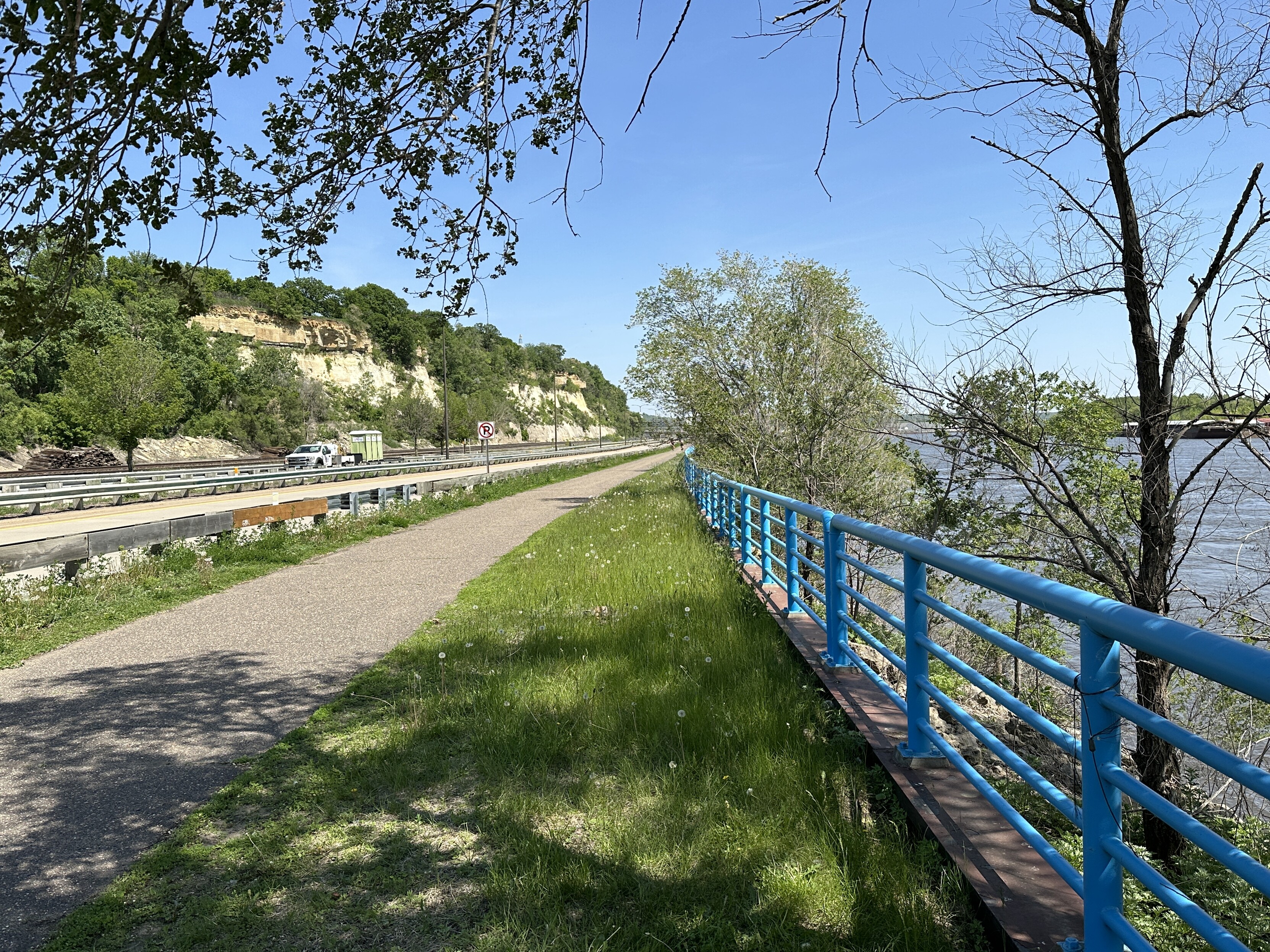 Road with truck on left, bike path in the middle, blue railing, then Mississippi River on the right