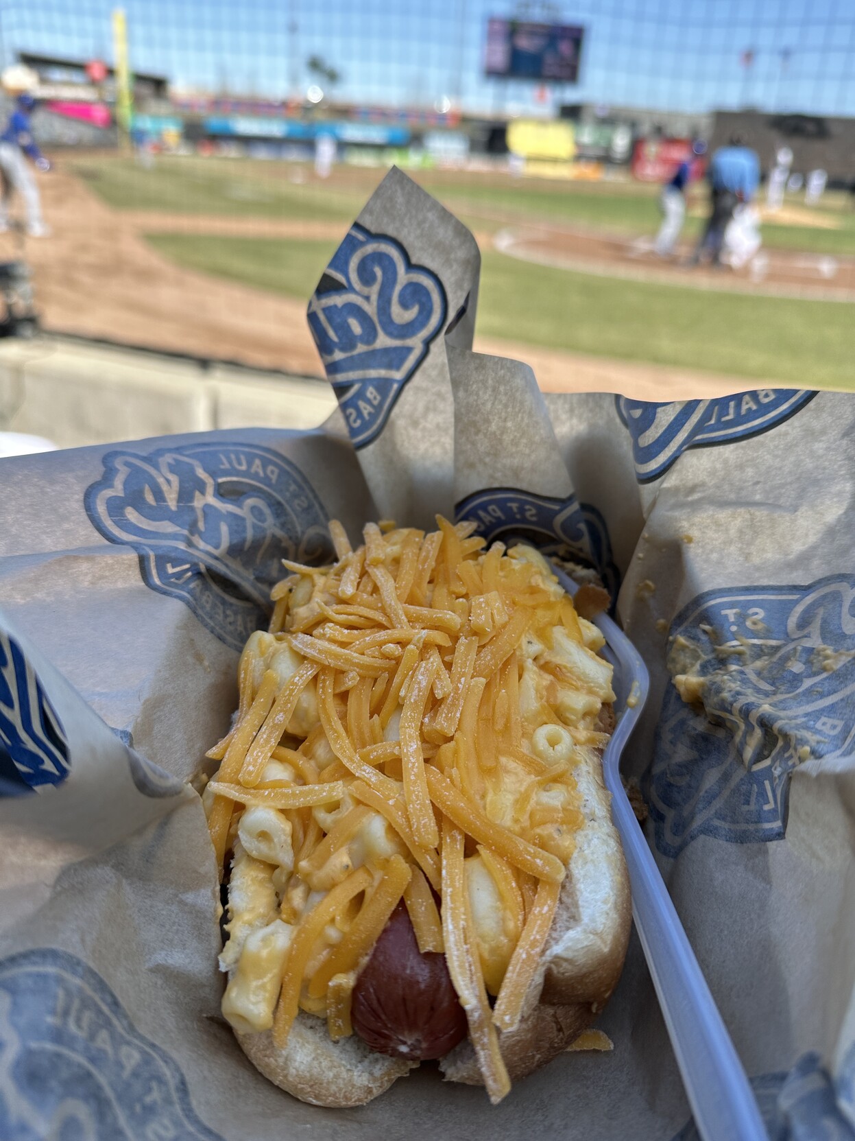 Mac and cheese hot dog with a sunny CHS Field baseball diamond in the background