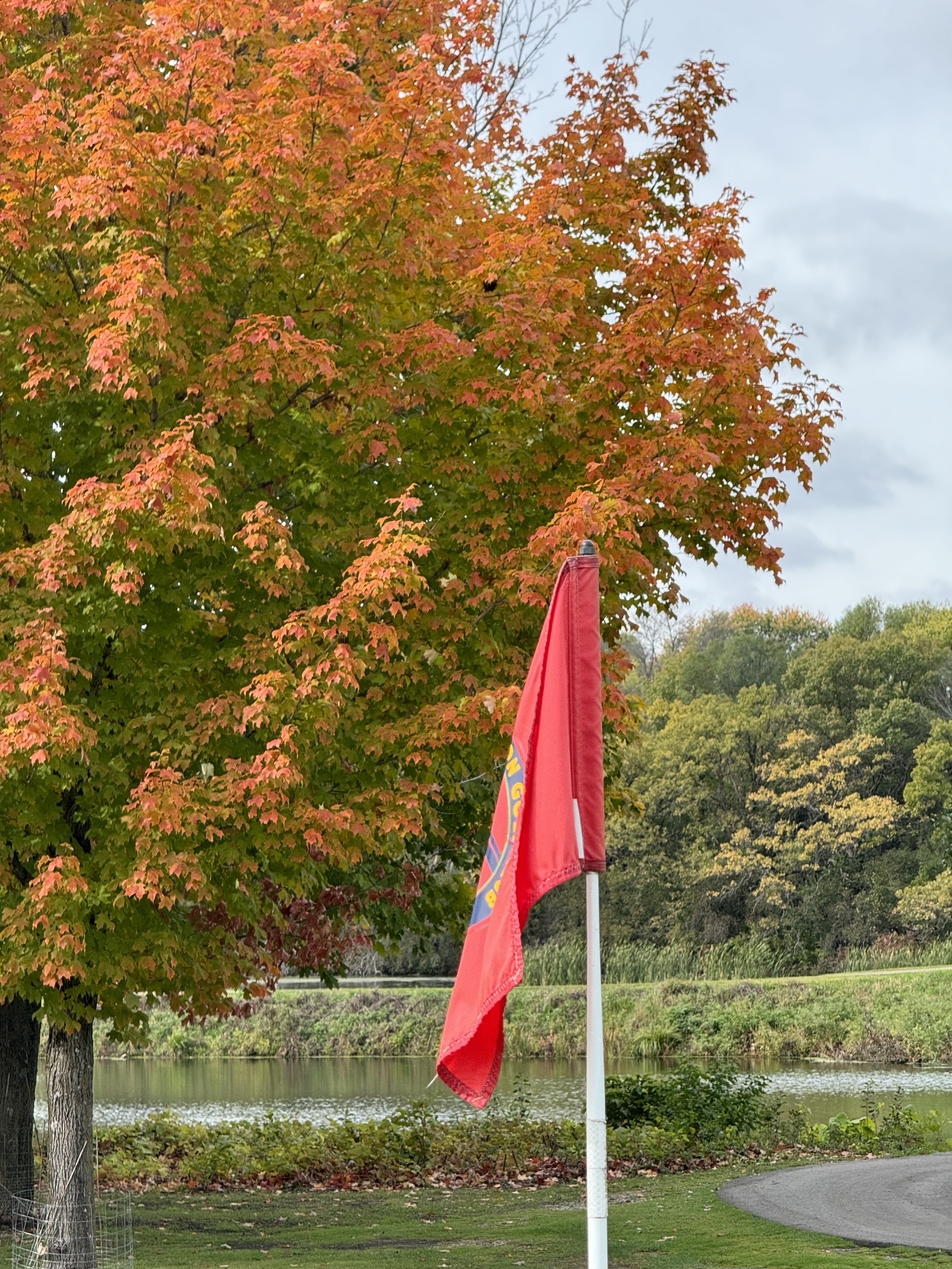 Flag stick at Cannon Golf Club in front of a tree in full fall colors