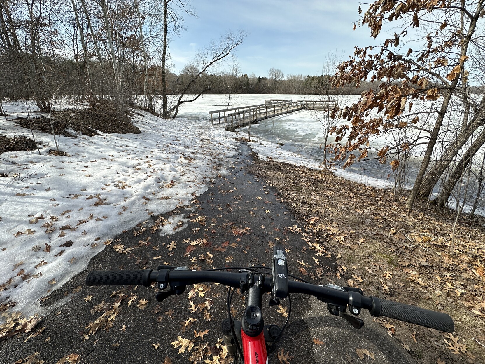 Handlebar pic from the Colby Lake trail in Woodbury, Minnesota, showing a fair amount of ice and snow (that is rapidly melting in the 70F temps)