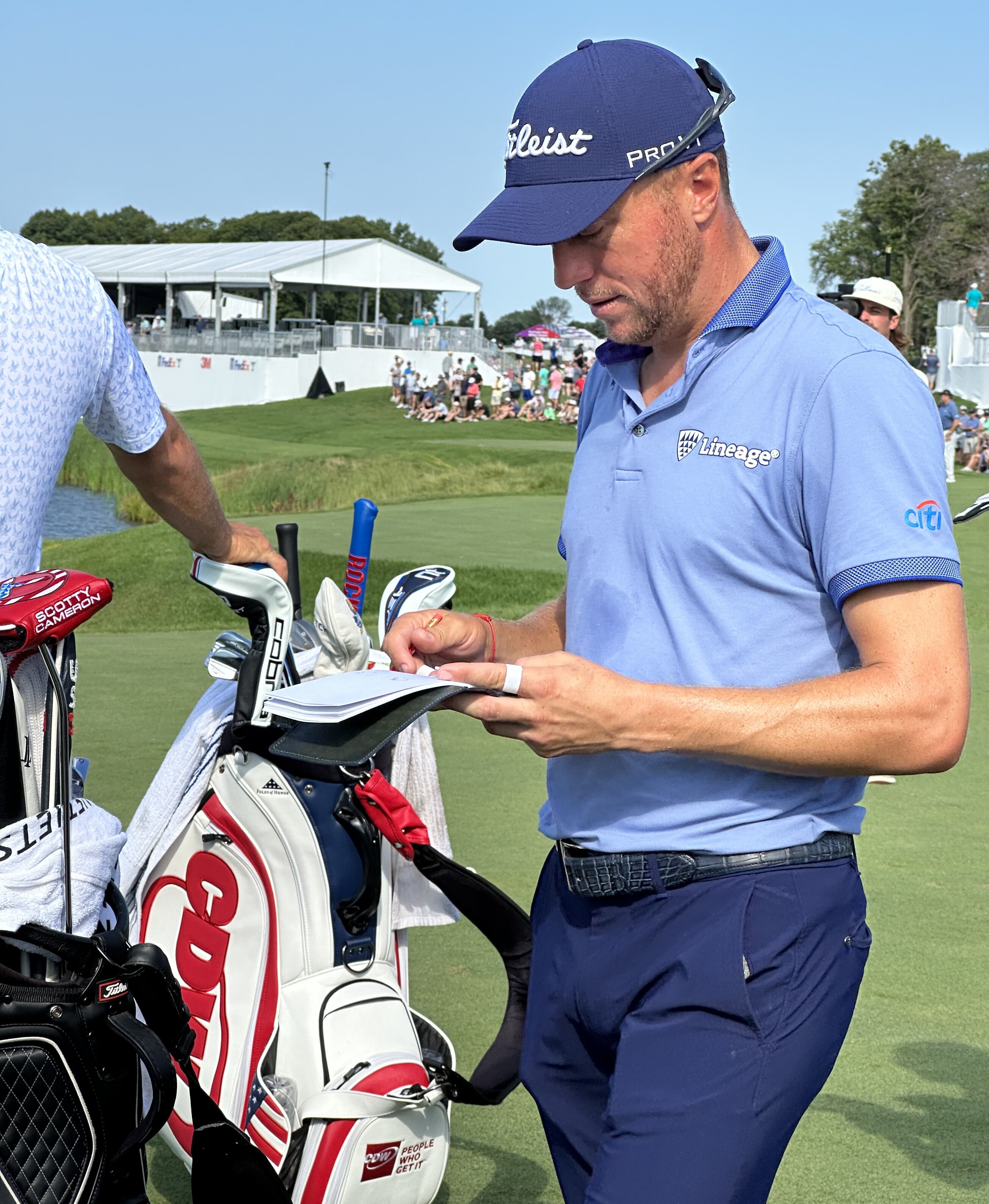 Close-up photo of Justin Thomas checking his yardage book on the 17th tee at the 3M Open golf tournament at TPC Twin Cities in Blaine, Minnesota