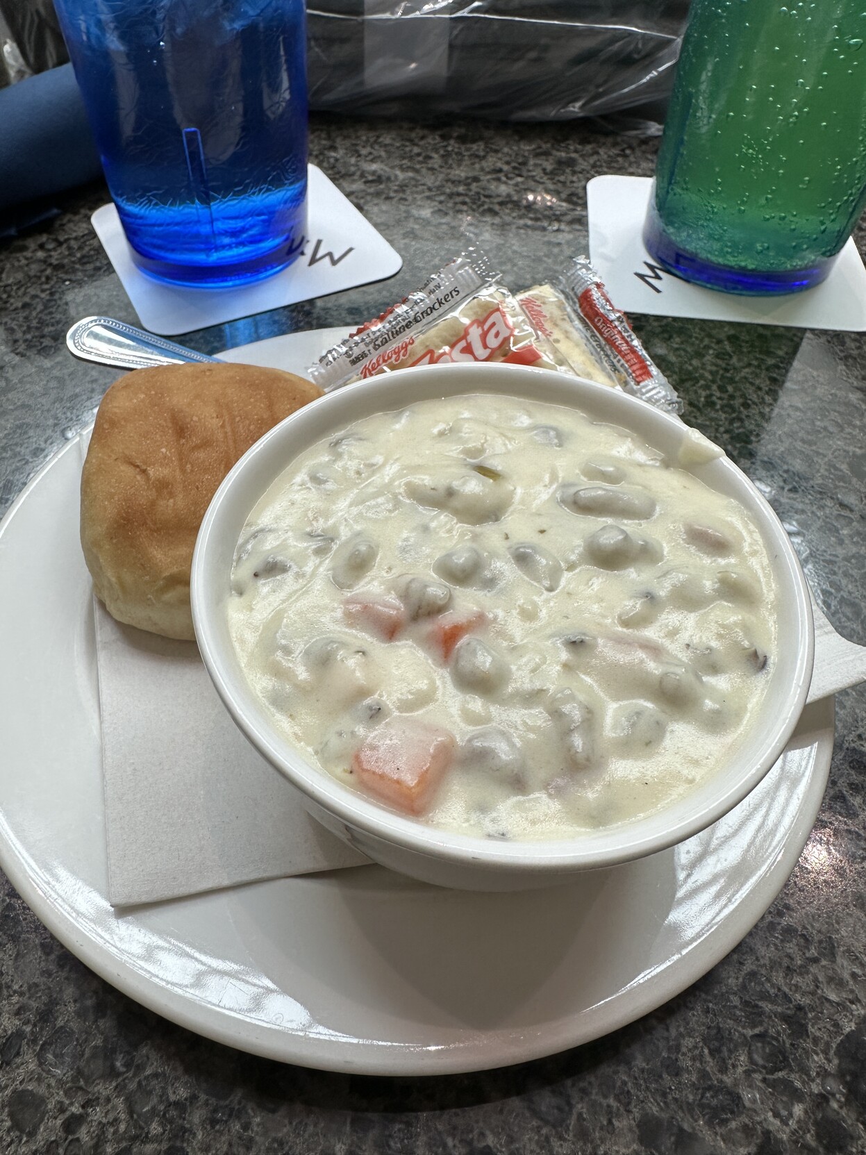 Bowl of chicken wild rice soup with a roll and crackers